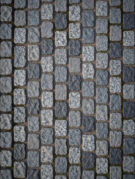 Grey cobblestone street texture, small stone blocks arranged in neat rows. Ground surface seamless pattern, natural granite material, pathway detail.