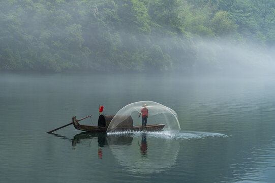 Fisherman Casting Net on Misty Forest Lake
