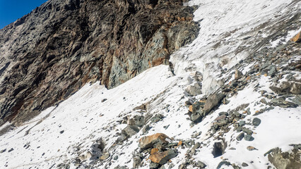Obraz premium Crevasse view during the Grossglockner hike, alpine mountain landscape with glacier and rugged rocky terrain, snowfields, and a stone cairn in High Tauern, national park