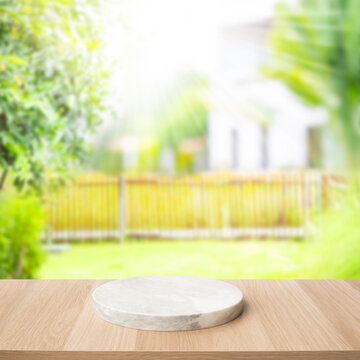 Selective focus.Wood table top with marble chopping board with blur garden and house area
