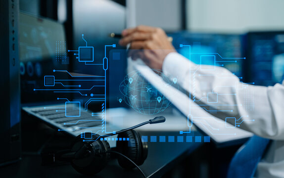 IT professional analyzes global logistics and circuit data via futuristic HUD screens. A headset rests on the desk