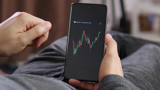 A user studies a rising stock chart on a smartphone, capturing mobile investing, bullish market sentiment and the growing role of retail traders in digital finance.