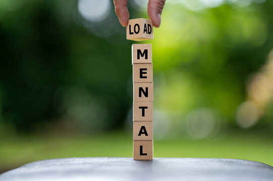Hand completes mental load on a tall wooden cube tower