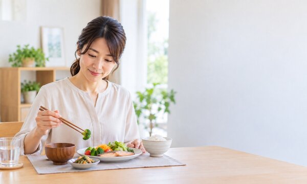 自宅で野菜中心の食事をとりながら健康的な食生活を送る日本人女性