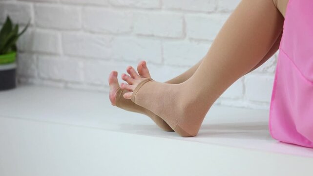 Woman wiggling toes in beige compression stockings. Open toe medical hosiery for leg fatigue relief and varicose veins care. Foot exercise wearing compression