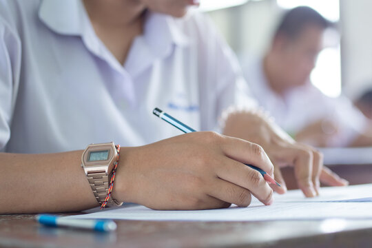 Close-up of Student Hand Writing on Exam Paper with Pen
High School Student Taking Standardized Test with Concentration on Wooden Desk