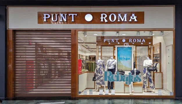 Entrada de tienda de ropa de mujer Punt Roma, con escaparate con cartel de Rebajas y con cierre met&aacute;lico cerrado, en centro comercial Islazul en Madrid, Espa&ntilde;a, 30 de junio de 2026