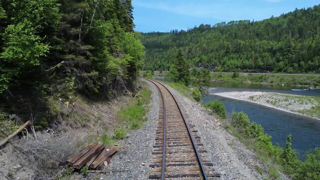 Drone footage documents a railway route through the Matapedia Valley where renewed ballast and stacked wooden ties signal ongoing infrastructure modernization efforts.