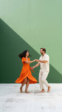 Romantic couple dancing together against a vibrant blue wall with dramatic geometric shadow