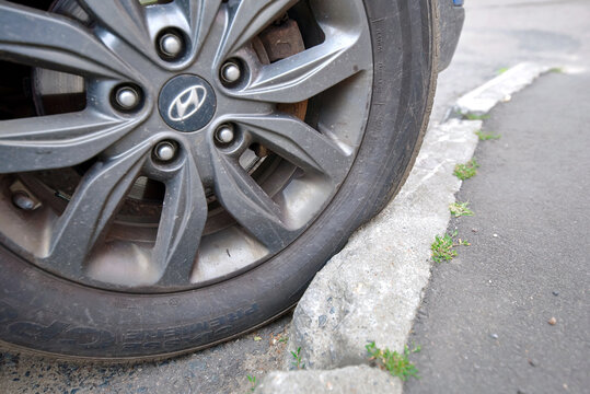 Minsk, Belarus. Jun 23, 2024. Vehicle rubber tire sidewall pressed tightly against street curb stone, strain deformation and scratch risk during tight parallel parking. Huyndai wheel squeezed