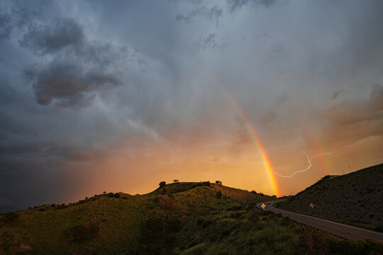 Rainbow and lightning storm over hillside on arizona highway 83