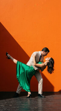 Romantic couple dancing together against a vibrant blue wall with dramatic geometric shadow