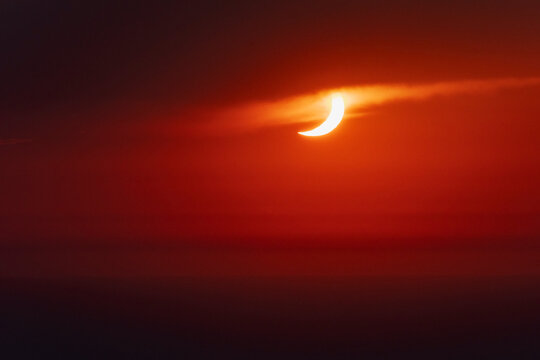 Solar eclipse crescent emerging through clouds over valldemossa