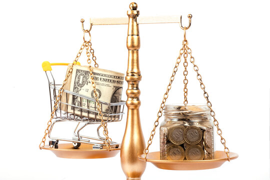 A glass jar containing 100 Kazakhstani tenge coins and a stack of US 1 dollar bills, placed on the pans of a golden balance scale.