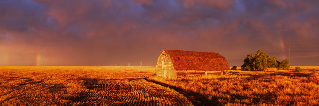 Old barn at Sunset with Rainbow over rural field