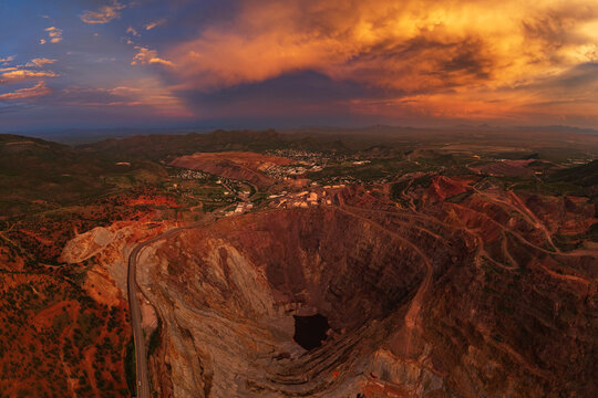 Open pit mine with stormy sunset sky and surrounding landscape
