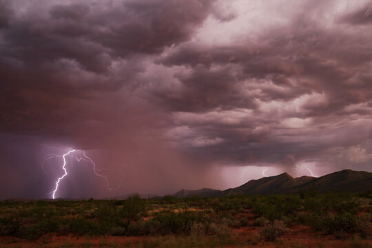 Lightning striking over desert storm with mountains