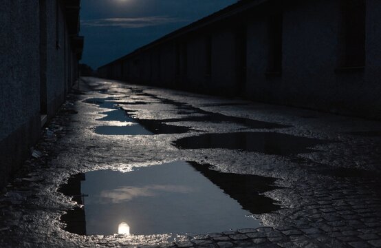 Moonlit wet alley with moon reflected in a rain puddle
