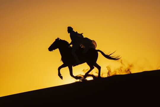 Horse Rider silhouette galloping on Desert dune