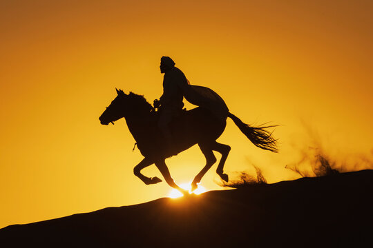 Berber Horseman riding horse over Desert dune