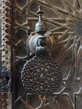 Ornate metal door knocker with intricate geometric patterns at medresa