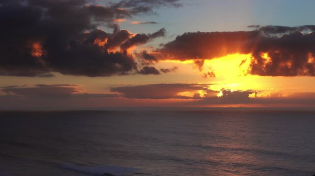 View of a vibrant sunset over the Atlantic Ocean with golden light rays breaking through dramatic clouds in Essaouira, Marrakesh-Safi, Morocco.