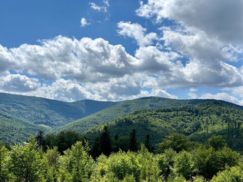 Lush green forested mountain slopes and rolling hills under dramatic clouds