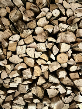 Fondo r&uacute;stico de le&ntilde;a cortada y apilada en plano completo mostrando texturas naturales de troncos de madera seca para chimenea