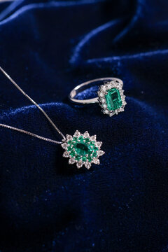 Elegant jewelry set featuring a silver-tone necklace with green gemstone pendant and a matching ring, displayed on luxurious dark blue velvet.