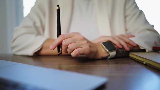 Close-up of businesswoman nervous hands at an office desk while contemplating project,illustrating emotional tension, workplace anxiety, overthinking and mental wellbeing challenges of modern work