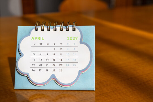 April 2027. Image of a pastel-colored desk calendar placed on a wooden desk.