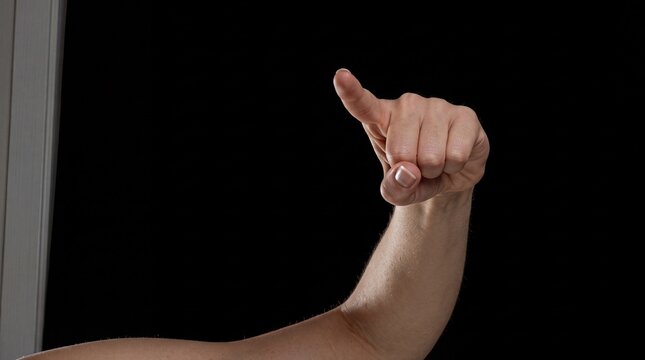 Close-up of human hand pointing forward with index finger on black background, expressing gesture communication