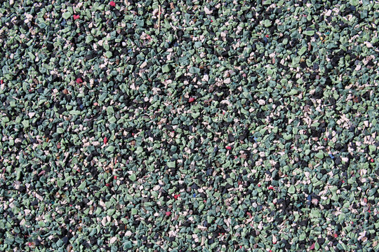Texture de surface rugueuse en granul&eacute;s de caoutchouc pour aire de jeux ou terrain d'athl&eacute;tisme, rev&ecirc;tement de sol sportif synth&eacute;tique souple de couleur bleu-vert.