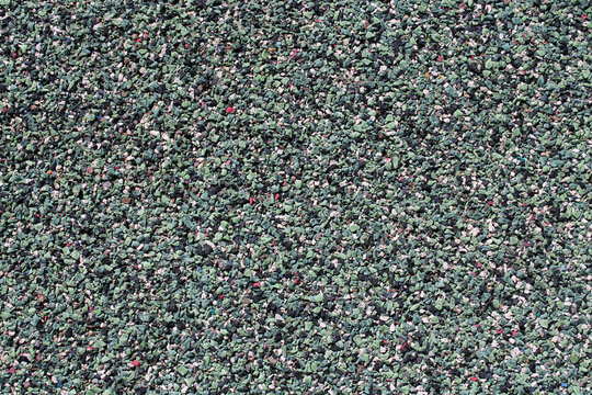 Texture de surface rugueuse en granul&eacute;s de caoutchouc pour aire de jeux ou terrain d'athl&eacute;tisme, rev&ecirc;tement de sol sportif synth&eacute;tique souple de couleur bleu-vert.