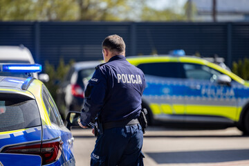 Policjant biegnie do radiowozu na akcję © FotoDax
