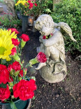 Ein Engel mit Blumen auf dem Friedhof auf einem Grab