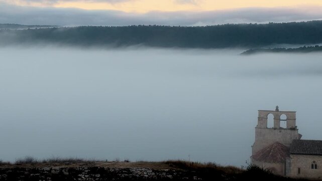 Peque&ntilde;a iglesia rom&aacute;nica de piedra construida sobre una colina rocosa con forma de barco al amanecer, con niebla en el Valle de Losa, Arquitectura medieval antigua, templo hist&oacute;rico rural, Pantale&oacute;n.