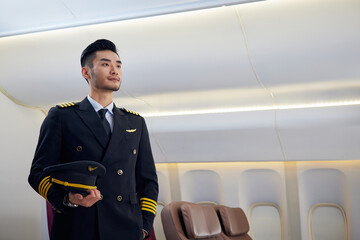 Confident airline pilot standing inside airplane cabin © LeNgoc