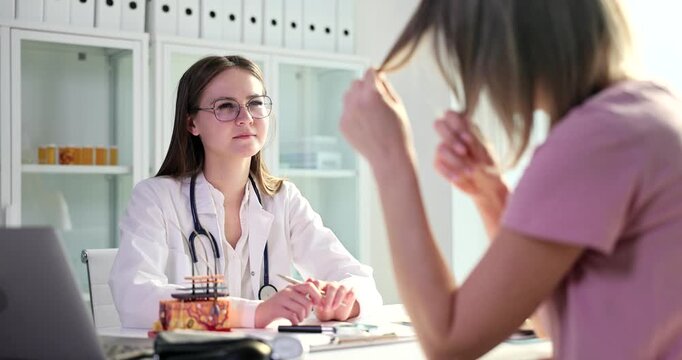 A doctor in a white coat listens intently during a consultation with a patient. They exchange thoughts in a bright, modern office, fostering a supportive environment.