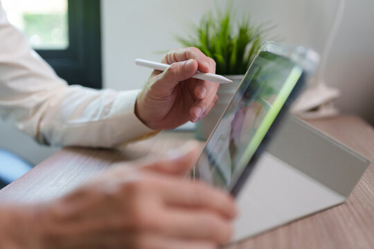 Businessman using stylus on a digital tablet at a desk, representing digital business, mobile technology, online work.