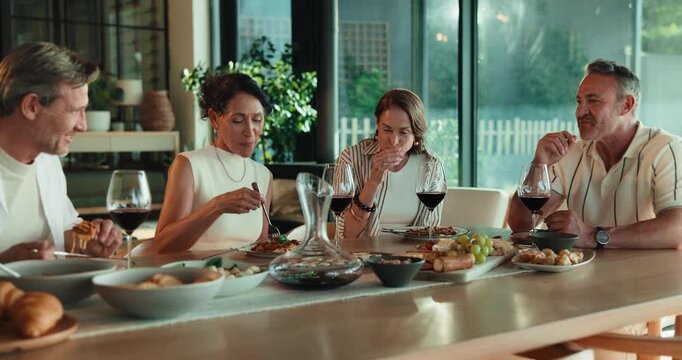 Relax, couple of friends and eating for dinner party, get together and bonding with meal compliment. Happy, mature people and food at dining table for social gathering, talking and enjoy dish in home