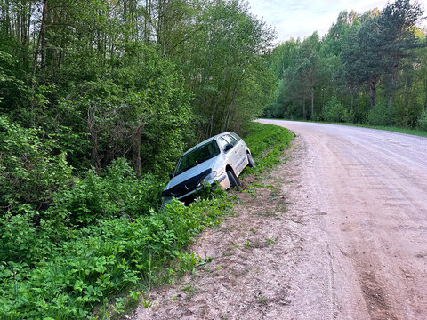 Car crash. `car went off road as result of accident. Driver did not exceed the speed limit, lost control, and went into ditch. Silver station wagon crashed off dirt road into forest ditch. Dirt road 