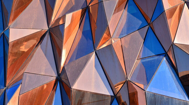 Faceted copper and blue glass panels form an abstract geometric architectural pattern