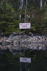 Obraz premium Small warning sign among mossy forest rocks