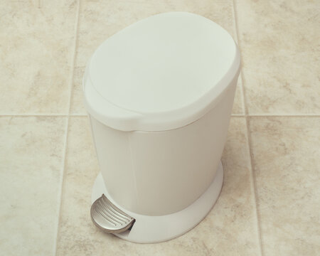 White trash can on kitchen floor.