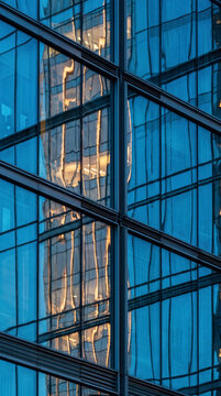 Sunlit glass corner facade reflects a golden high rise tower in triangular pattern