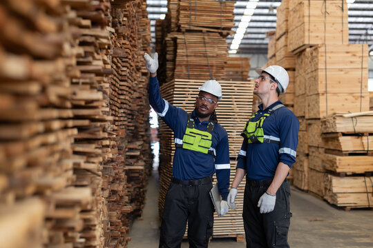 Workers discussing tasks in a wood storage area in a warehouse