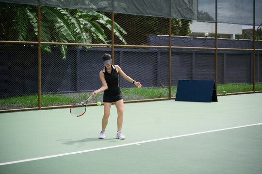 Asian Woman Playing Tennis on Outdoor Court During Daytime Leisure Activity
