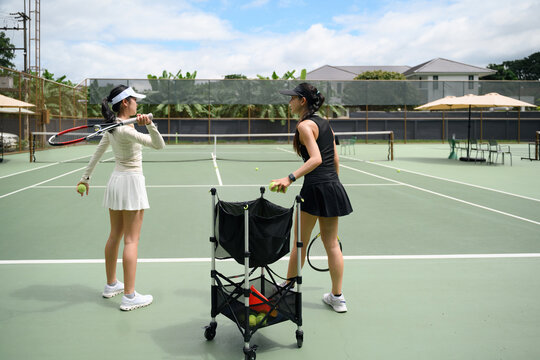 Female Tennis Coach Teaching Student Swing Technique on Outdoor Court with Ball Cart