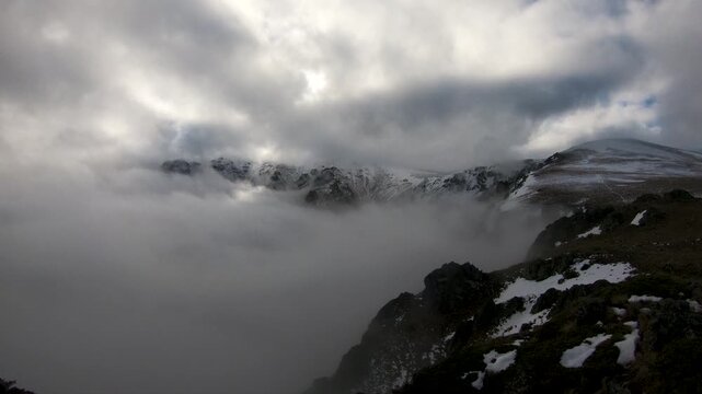 View of the Balkan Mountains covered in snow with thick clouds rolling over the peaks in Lovech, Bulgaria.